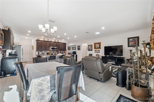 dining space featuring ornamental molding, light tile patterned floors, and a chandelier