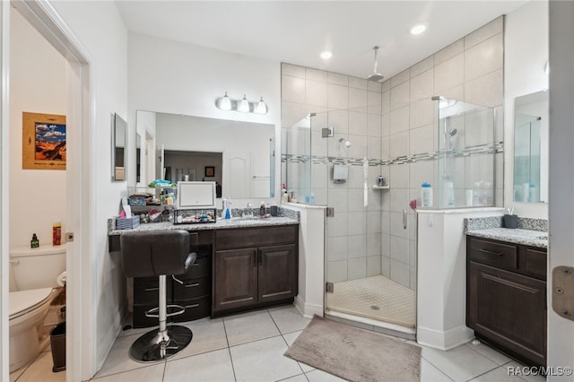 bathroom featuring tile patterned flooring, vanity, a shower with shower door, and toilet