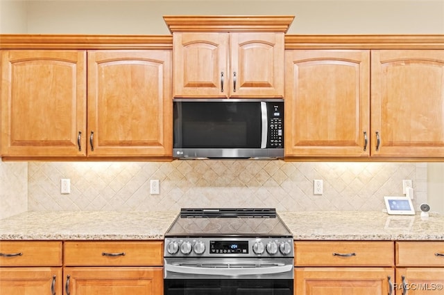 kitchen featuring tasteful backsplash, light stone countertops, and stainless steel appliances