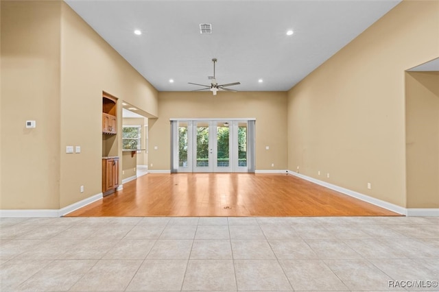 unfurnished living room featuring light tile patterned flooring, ceiling fan, and french doors