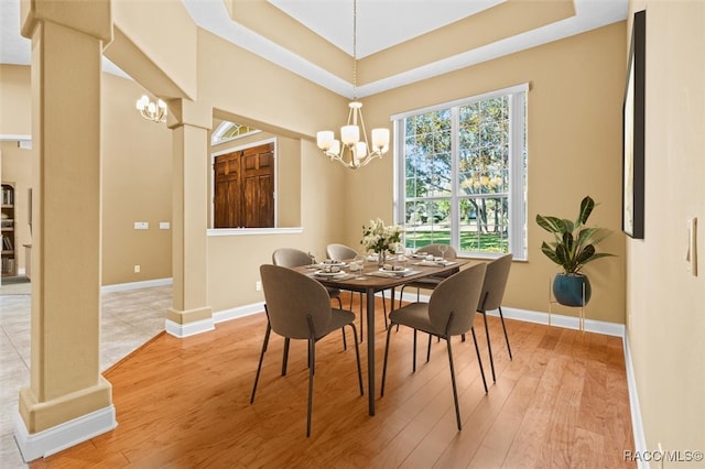 dining space with ornate columns, hardwood / wood-style floors, and an inviting chandelier