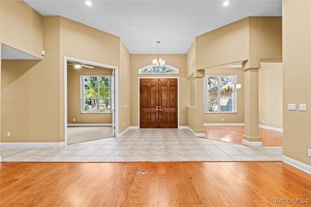 entrance foyer with an inviting chandelier, light hardwood / wood-style flooring, and ornate columns