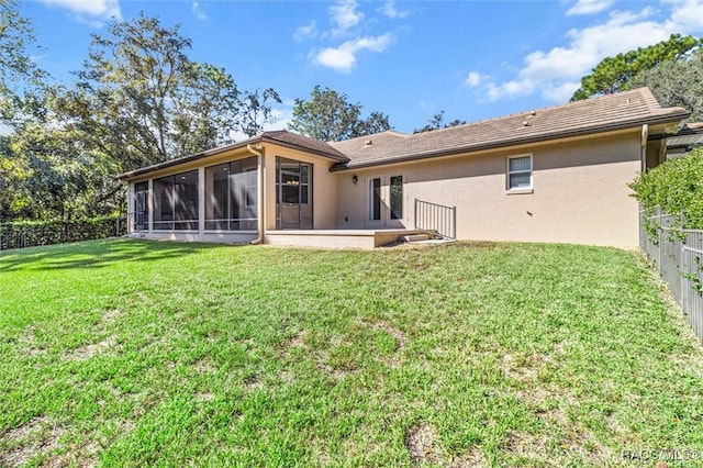 rear view of property featuring a lawn, a sunroom, and a patio area