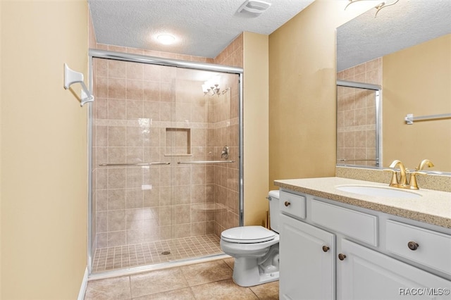 bathroom with tile patterned flooring, vanity, a textured ceiling, a shower with shower door, and toilet