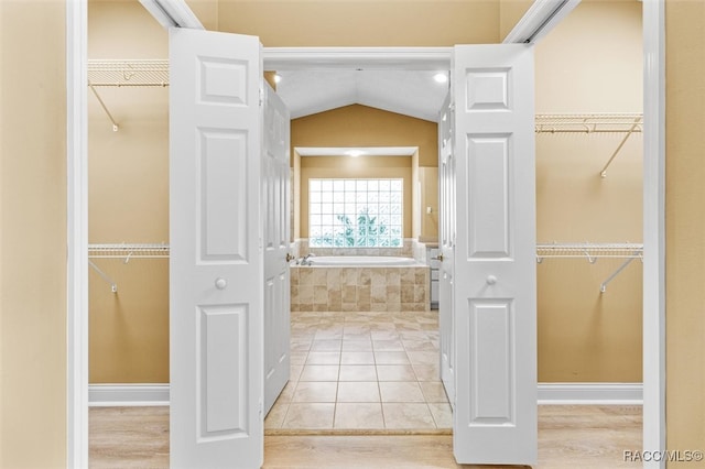 bathroom featuring lofted ceiling, tiled bath, and tile patterned flooring