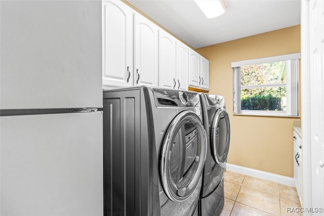 laundry area with washer and clothes dryer, cabinets, and light tile patterned flooring