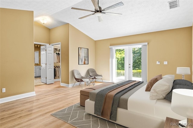 bedroom featuring lofted ceiling, access to exterior, light hardwood / wood-style flooring, and a textured ceiling