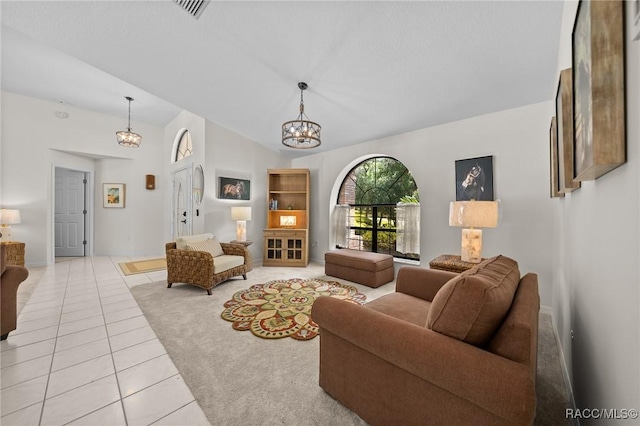 living area featuring light tile patterned flooring, baseboards, visible vents, a notable chandelier, and lofted ceiling