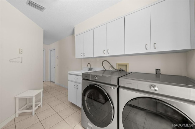 washroom featuring visible vents, a sink, baseboards, separate washer and dryer, and cabinet space