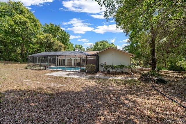 back of property featuring a lanai and an outdoor pool