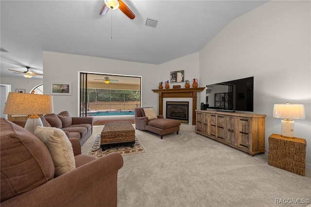 living room featuring lofted ceiling, visible vents, a ceiling fan, and light carpet
