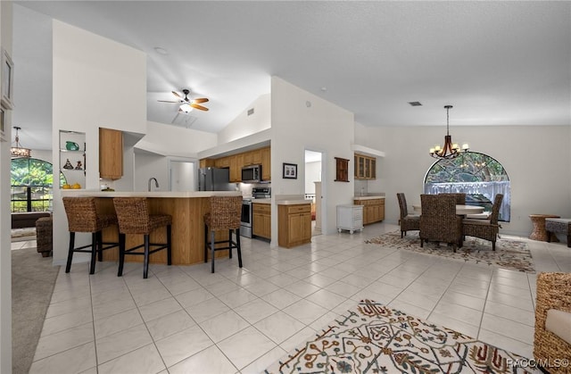 interior space with a peninsula, a kitchen breakfast bar, open floor plan, brown cabinetry, and appliances with stainless steel finishes