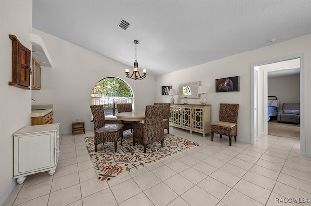 dining room featuring lofted ceiling, an inviting chandelier, visible vents, light tile patterned floors, and baseboards