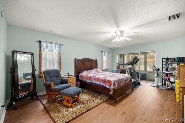 11271 SE 136th Ter, Dunnellon, FL 34431 - bedroom featuring light wood-type flooring, multiple windows, access to exterior, a ceiling fan, and a textured ceiling