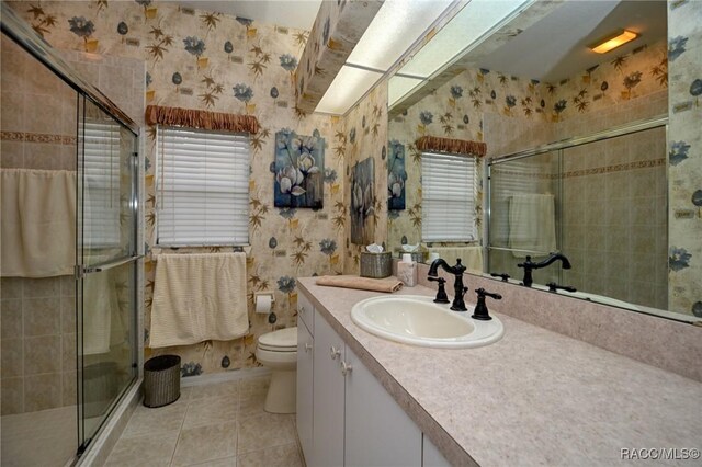 full bathroom with toilet, wallpapered walls, tile patterned flooring, a shower stall, and vanity