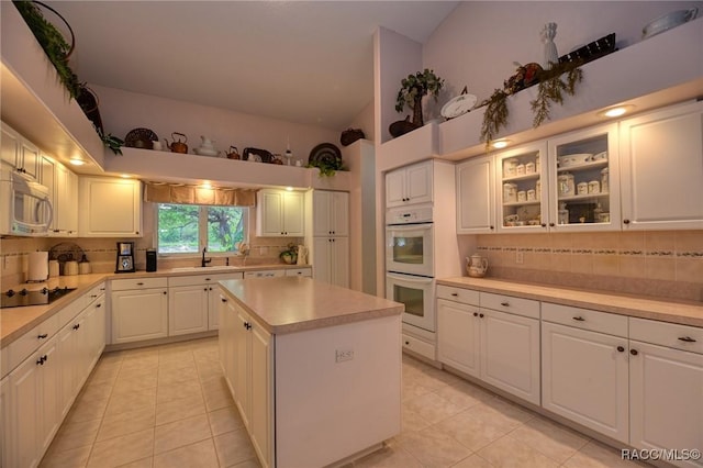 kitchen featuring tasteful backsplash, white double oven, light countertops, stainless steel microwave, and lofted ceiling