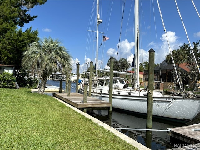 view of dock with a yard and a water view