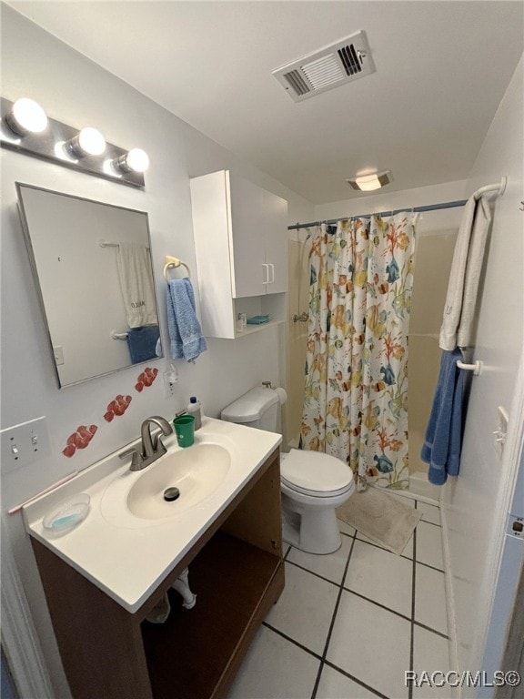 bathroom featuring tile patterned flooring, vanity, toilet, and walk in shower