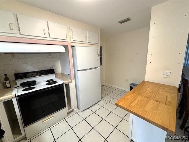 kitchen with light tile patterned flooring, range hood, white appliances, decorative backsplash, and white cabinets