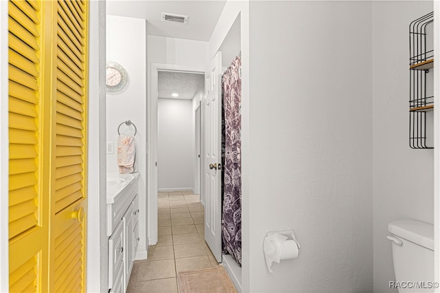 bathroom with toilet, a textured ceiling, vanity, and tile patterned floors