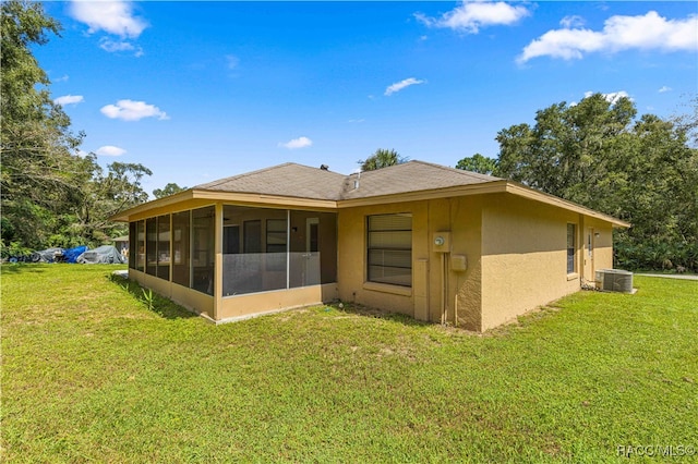 back of property featuring a sunroom, a yard, and central AC