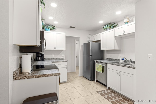 kitchen featuring a textured ceiling, stainless steel appliances, sink, white cabinets, and light tile patterned flooring