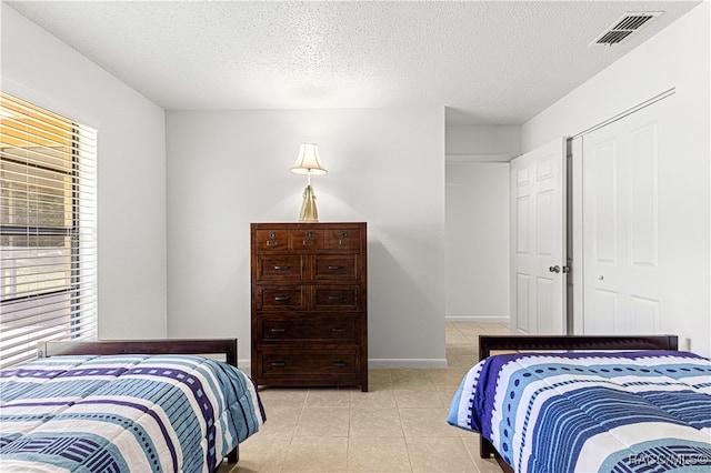 bedroom with a closet, light tile patterned flooring, and a textured ceiling