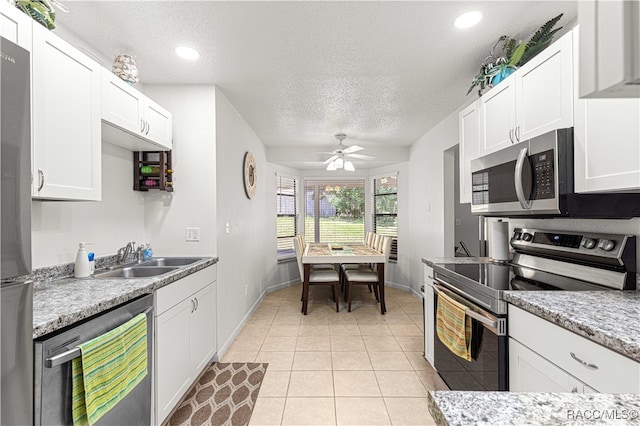 kitchen with appliances with stainless steel finishes, white cabinetry, ceiling fan, and sink