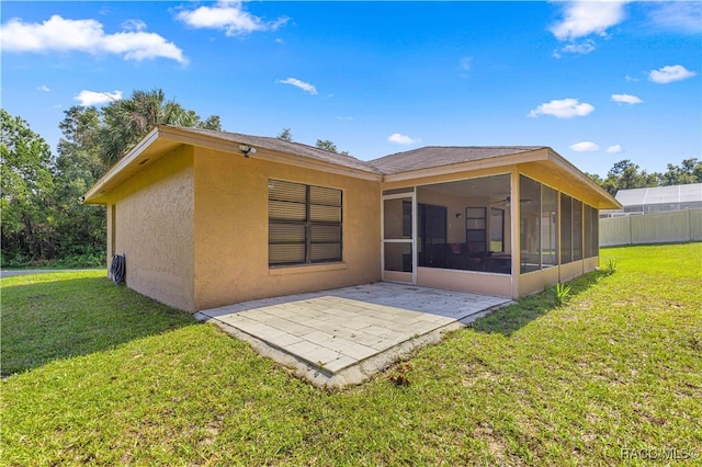 rear view of house with a lawn, a patio area, and a sunroom