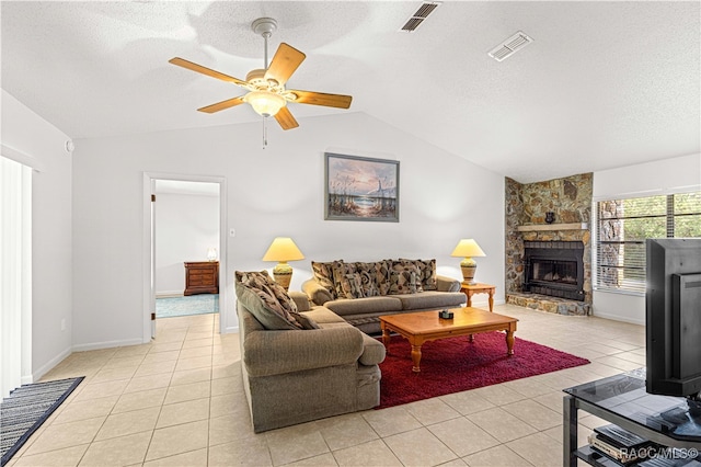 living room with a textured ceiling, vaulted ceiling, a stone fireplace, and light tile patterned flooring