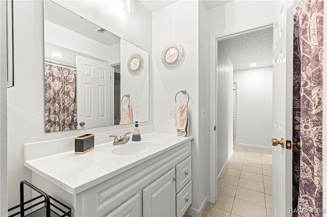 bathroom with tile patterned flooring, vanity, and a textured ceiling