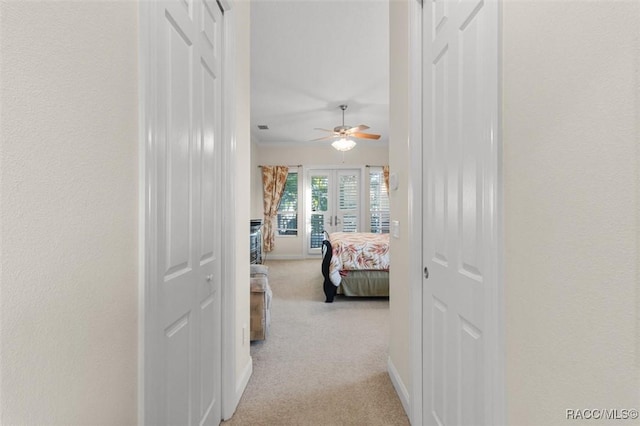 corridor with light carpet and french doors