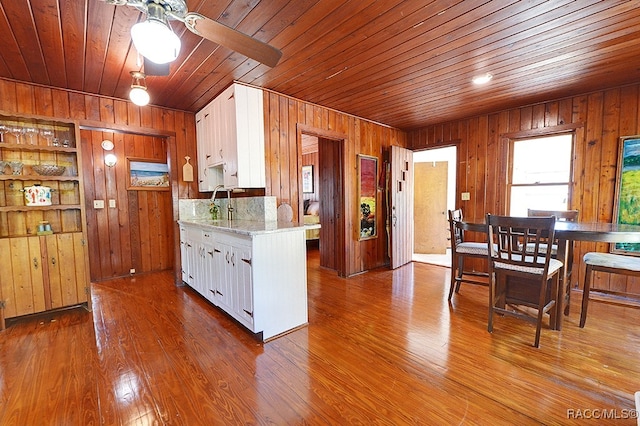 kitchen with white cabinets, hardwood / wood-style floors, wooden walls, and wood ceiling