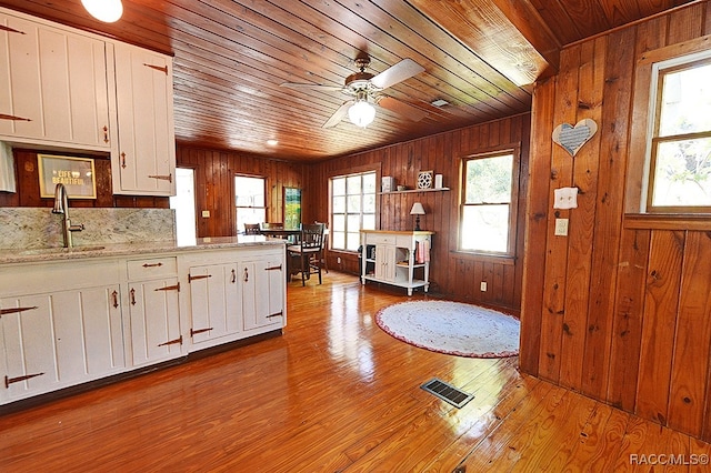 kitchen featuring white cabinets, wood-type flooring, a healthy amount of sunlight, and sink