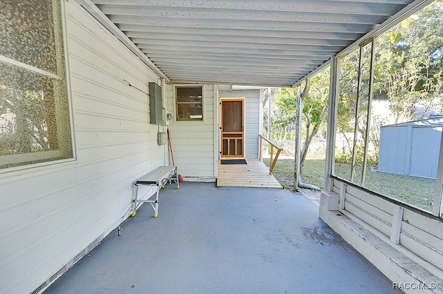 view of patio with electric panel, a deck, and a storage shed