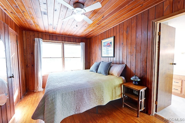 bedroom featuring light wood-type flooring, wooden ceiling, ceiling fan, and wooden walls