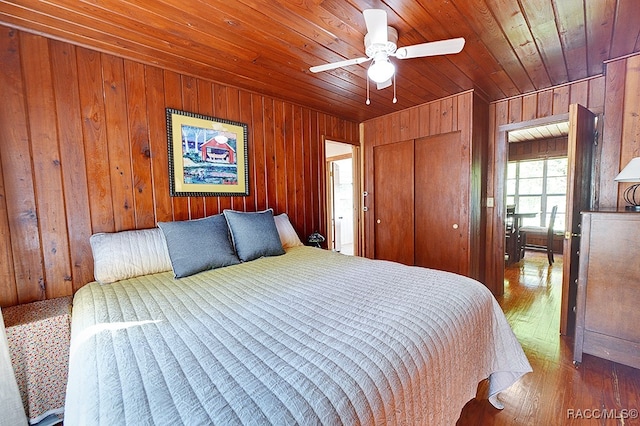 bedroom with wood walls, ceiling fan, wood ceiling, and hardwood / wood-style flooring