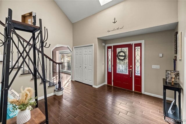 entrance foyer with arched walkways, stairway, wood finish floors, and baseboards