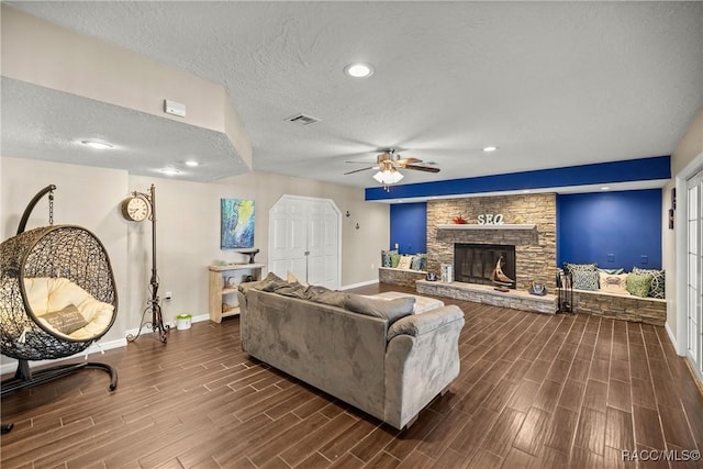 living room featuring baseboards, visible vents, a textured ceiling, wood finish floors, and a fireplace