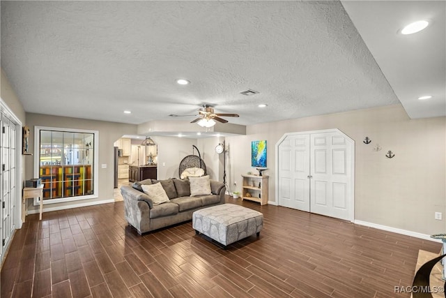 living area with dark wood-style flooring, recessed lighting, visible vents, a textured ceiling, and baseboards