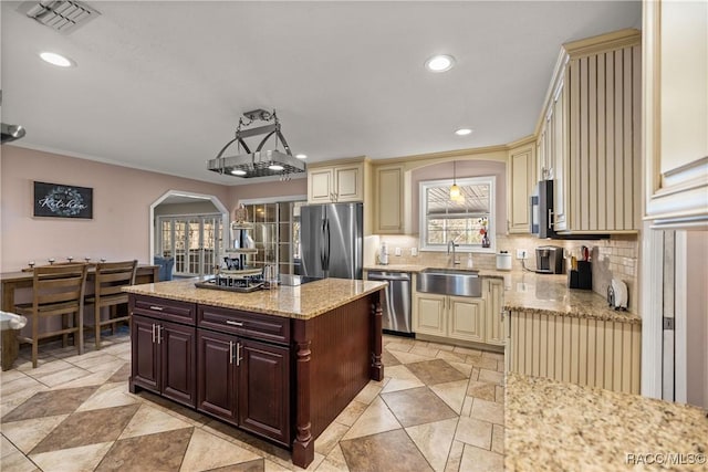 kitchen with arched walkways, cream cabinetry, stainless steel appliances, visible vents, and a sink