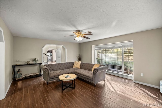 living room with arched walkways, ceiling fan, a textured ceiling, stairs, and wood tiled floor