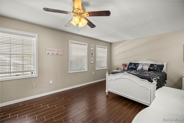 bedroom featuring dark wood-style floors, multiple windows, baseboards, and a ceiling fan