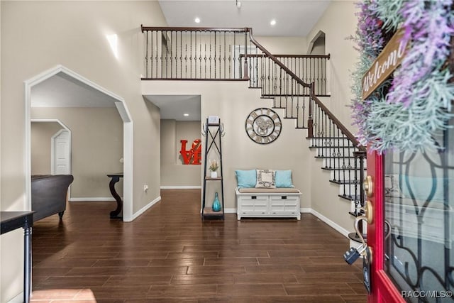 entrance foyer featuring baseboards, arched walkways, wood finished floors, a high ceiling, and recessed lighting