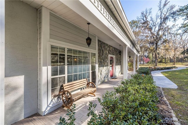 view of exterior entry with covered porch and stucco siding