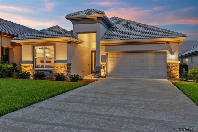 prairie-style home featuring stone siding, a tile roof, an attached garage, and concrete driveway