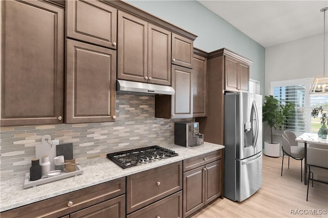 kitchen with appliances with stainless steel finishes, decorative light fixtures, under cabinet range hood, and dark brown cabinets