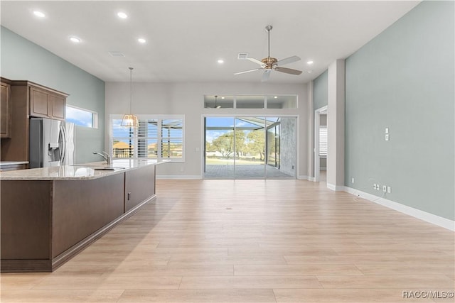 kitchen featuring light stone counters, decorative light fixtures, stainless steel fridge with ice dispenser, light wood-type flooring, and ceiling fan