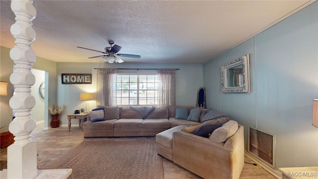 living room featuring ceiling fan and a textured ceiling