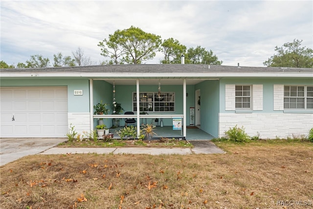 single story home with covered porch, a garage, and a front lawn